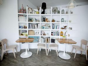 two tables and chairs in a room with bookshelves at We Stay Inn in Eluan