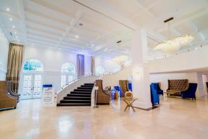 a large lobby with a staircase and blue chairs at The Alexander Beach Residences in Miami Beach