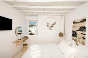 a white room with a bed and a mirror at Villa Loom Mykonos Town in Mikonos