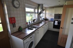 a kitchen with a sink and a washing machine at Beautiful coastal bungalow, Sennen, Porthcurno,sea in Penzance