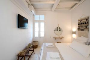 a white room with a bed and a tv on a wall at Villa Loom Mykonos Town in Mikonos
