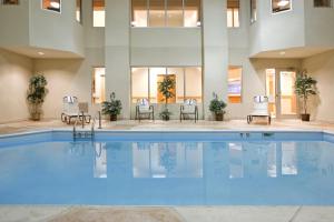 una gran piscina en un hotel con sillas y mesas en Holiday Inn Express Hotel & Suites Grove City, an IHG Hotel en Grove City
