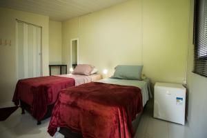 a room with two beds and a refrigerator at Palhoça da Colina in Fernando de Noronha