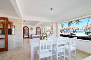 a dining room with a white table and chairs and the beach at La Flor del Caribe Beach & SPA in Punta Cana