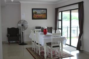 un comedor blanco con una mesa y sillas blancas en Tuscany By The Sea, en Port Edward