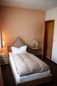 a bedroom with a bed with a table and a door at Hotel- Restaurant Kerzan´s in Dortmund