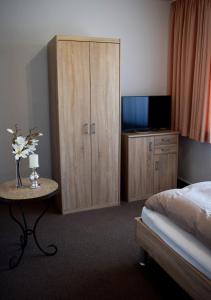 ein Schlafzimmer mit einem Bett und einem Schrank mit einem TV in der Unterkunft Hotel- Restaurant Kerzan´s in Dortmund