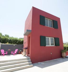une maison rouge avec des chaises roses et une table dans l'établissement Entire independent maisonette near Heraklion Pottery Classes, à Petrokefalo