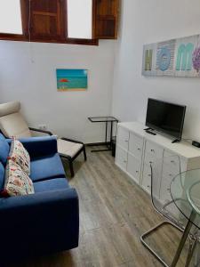 a living room with a blue couch and a tv at HomeForGuest Cozy loft with parking next to the Arucas Cathedral in Arucas