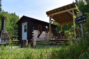 uma pequena cabana de madeira com toldo e um alpendre em Bois Rond Expérience em Saguenay
