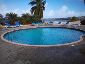 a swimming pool with chairs and a beach at Studio Marazul in Sabana Westpunt