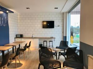 Albergue O Burgo في أو بيدروزو: مطعم به طاولات وكراسي وتلفزيون على الحائط
