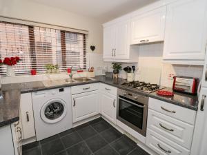 a kitchen with white cabinets and a washer and dryer at Valentines Cottage in Stratford-upon-Avon