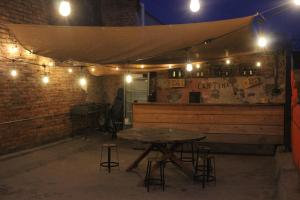 a table with stools in front of a bar at night at Sukha Hostel San Luis in San Luis Potosí