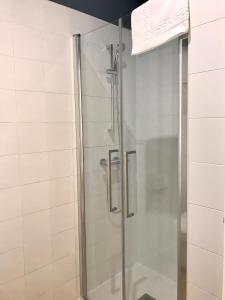 La salle de bains est pourvue d'une douche avec une porte en verre. dans l'établissement Albergue O Burgo, à O Pedrouzo