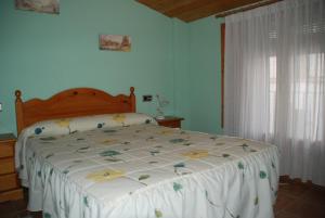 a bedroom with a bed with a white comforter and a window at Casa La Catalina in Beceite