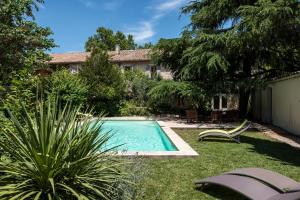 a swimming pool in the yard of a house at Hôtel Mas Vidau Porte des Alpilles in Saint-Étienne-du-Grès