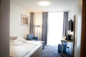 a hotel room with a bed and a blue chair at Hotel Pfefferhöhe Alsfeld in Alsfeld