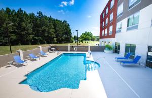 a swimming pool on a patio with chairs and a building at Holiday Inn Express & Suites Greenwood Mall, an IHG Hotel in Greenwood