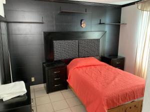 ein Schlafzimmer mit einem roten Bett und einer schwarzen Wand in der Unterkunft Boutique Gym Salon juegos Tv Oficina Sanitizada in Toluca de Lerdo