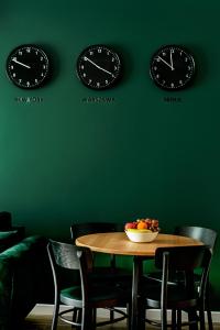 a table with chairs and two clocks on a green wall at Apartament Centrum XL - Komfortowe Noclegi in Piaseczno