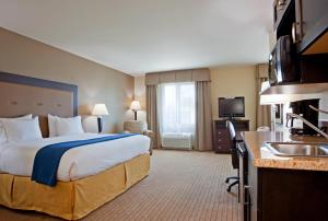 a hotel room with a large bed and a kitchen at Holiday Inn Express & Suites Madison-Verona by IHG in Verona