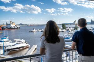 a man and a woman standing on a balcony looking at boats at Park Point Marina Inn in Duluth
