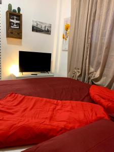 um quarto com uma cama vermelha e uma televisão de ecrã plano em Appartamento “La Corte” em Paderno Dugnano