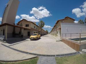 un coche amarillo estacionado en un estacionamiento junto a los edificios en Lençóis Ville Residence - CHALE 22, en Barreirinhas