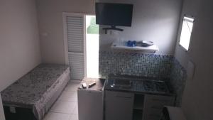 a small kitchen with a stove and a bed at Kitnets & Flats in Ubatuba