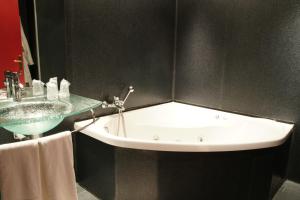 La salle de bains est pourvue d'un lavabo et d'une baignoire. dans l'établissement Hôtel et Restaurant Le Regina, au Puy-en-Velay