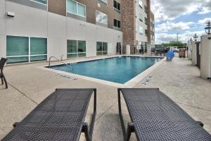 a swimming pool in a building with two benches at Holiday Inn Express & Suites - Houston East - Beltway 8, an IHG Hotel in Cloverleaf
