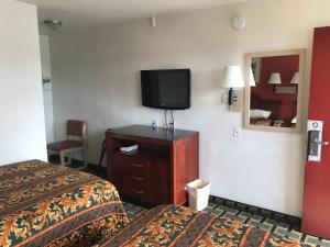 a hotel room with two beds and a flat screen tv at Travel Inn in Greensboro