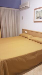 a bedroom with a bed with yellow sheets and a window at Hostal El Altet in El Alted