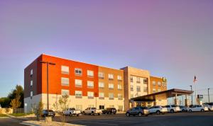 un edificio con coches estacionados en un estacionamiento en Holiday Inn Express & Suites Tulsa NE, Claremore, an IHG Hotel, en Claremore