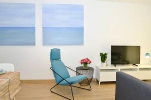 ein Wohnzimmer mit einem blauen Stuhl und einem TV in der Unterkunft CASA FELIPA, UNA ESTANCIA ÚNICA EN LA COSTA BLANCA in Guardamar del Segura