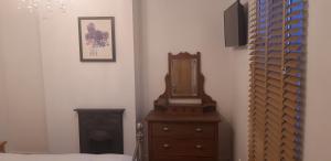 a bedroom with a dresser and a mirror on a dresser at Bodhi Tree Cottage - Grove Road Cottages in Stratford-upon-Avon