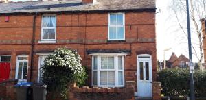 uma casa de tijolos vermelhos com portas e janelas brancas em Bodhi Tree Cottage - Grove Road Cottages em Stratford-upon-Avon