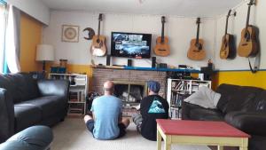 dos hombres sentados en una sala de estar viendo una tele en Kelowna International Hostel, en Kelowna