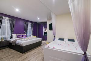 Dormitorio púrpura con cama y bañera en Anchan Hotel & Spa, en Hua Hin
