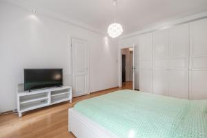 a white bedroom with a bed and a flat screen tv at CITYSTAY Plac Walowy Gdansk in Gdańsk