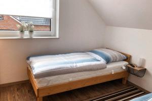 Bett in einem Zimmer mit Fenster in der Unterkunft Modernes Ferienhaus an der Kapelle in Emsbüren