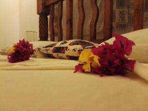 a bed with two pillows and flowers on it at Nyumba Nicole in Watamu