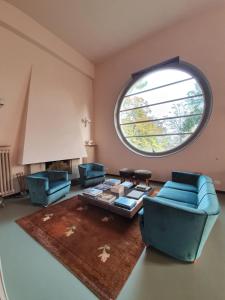 a living room with blue chairs and a large window at Villa Gotti Charming Rooms in Bologna
