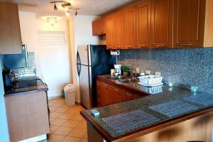 a kitchen with wooden cabinets and a black refrigerator at Wave View Village - Beach Front - Luxury Spot in Rincon