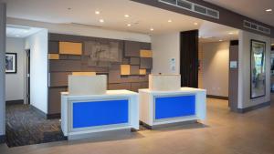 a lobby with two white tables and a blue wall at Holiday Inn Express & Suites - Jacksonville W - I295 and I10 by IHG in Jacksonville +35 photos
