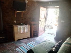 a living room with a tv and a couch and a door at Refúgio do Raposo/CASA Altair in Montes da Senhora