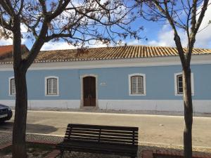 un bâtiment bleu avec un banc devant lui dans l'établissement Casa Largo do Poço Guesthouse, à Alvor