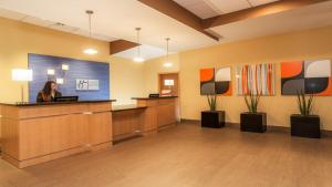 a woman sitting at a reception desk in an office lobby at Holiday Inn Express Fort Lauderdale Airport South, an IHG Hotel in Dania Beach