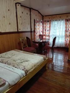 1 dormitorio con 1 cama, mesa y sillas en Koreen Guest House, en Banaue